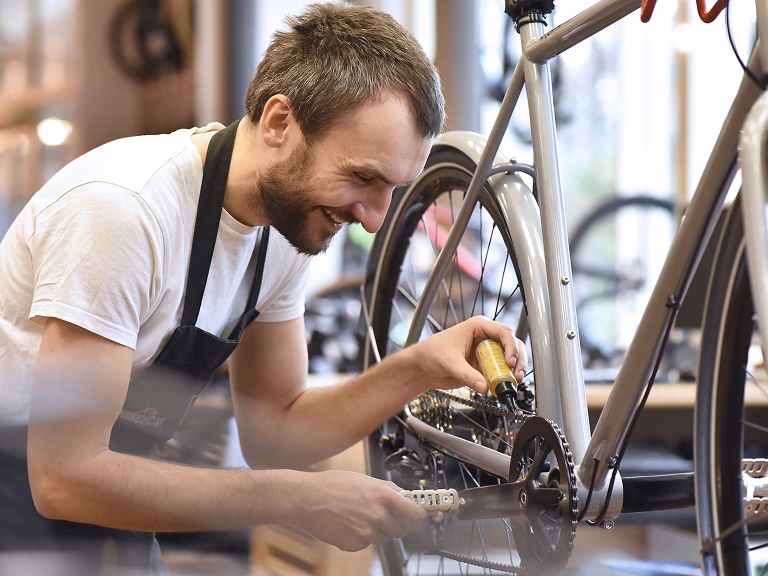 Commerçant souriant qui répare un vélo dans son magasin de cycles