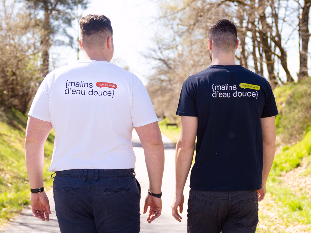 Yanis et Nael marchent de dos sur un chemin, en t-shirts Malins d'eau douce